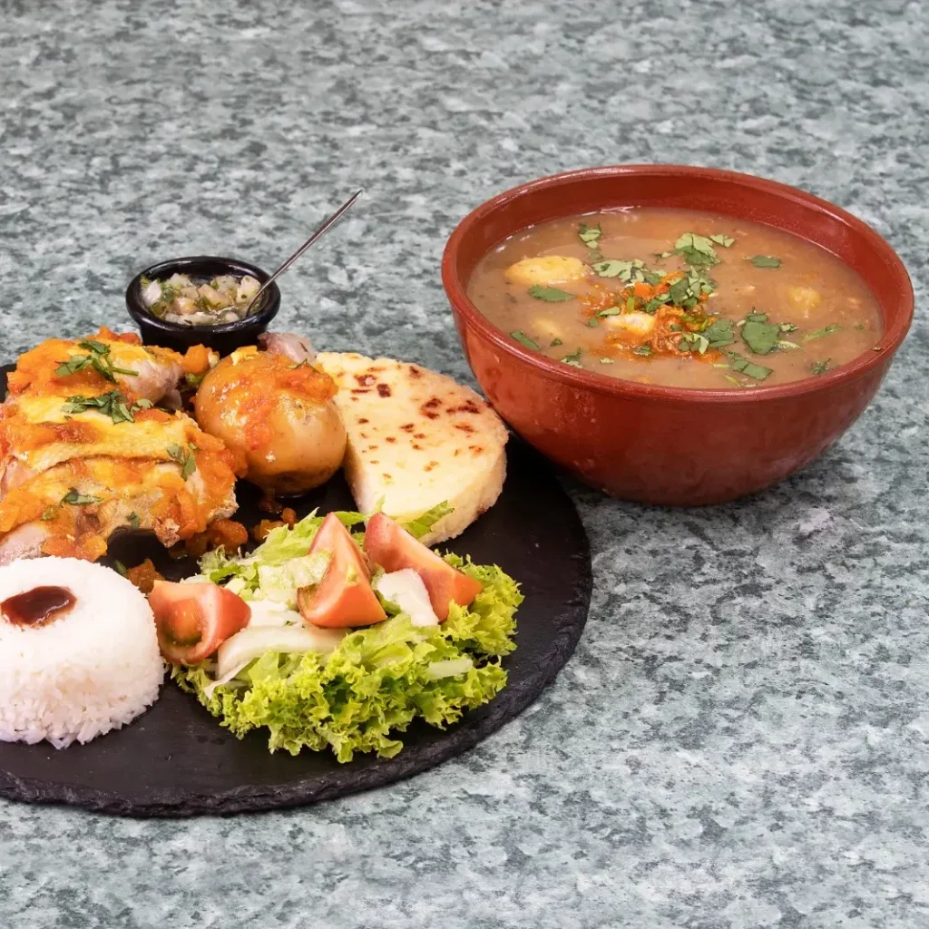 Sancocho colombiano de pollo o costilla con arroz, ensalada, aguacate, arepa y patacón